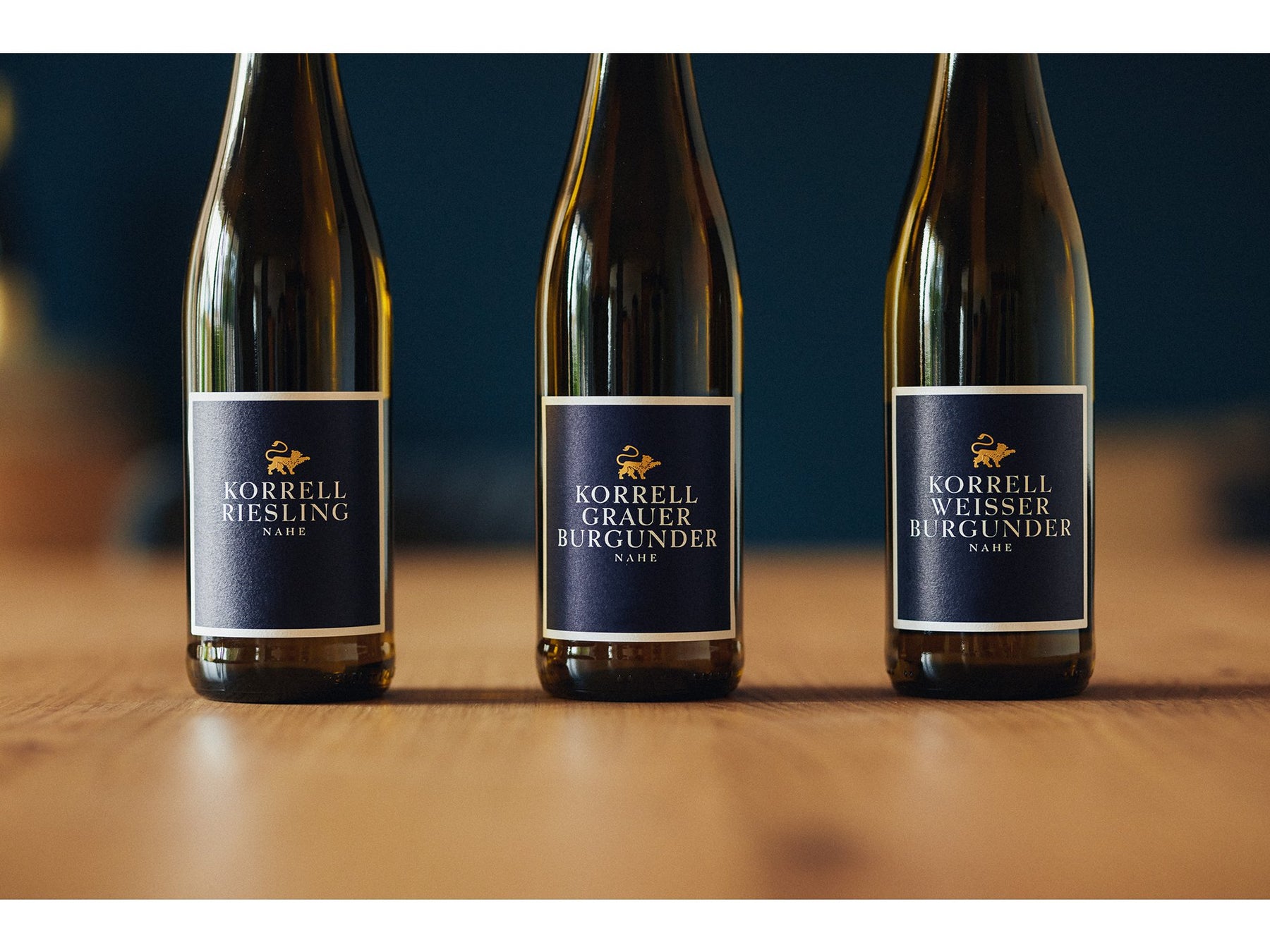 Riesling, Grauburgunder und Weißburgunder Flaschen auf Tisch vor dunklem Hintergrund