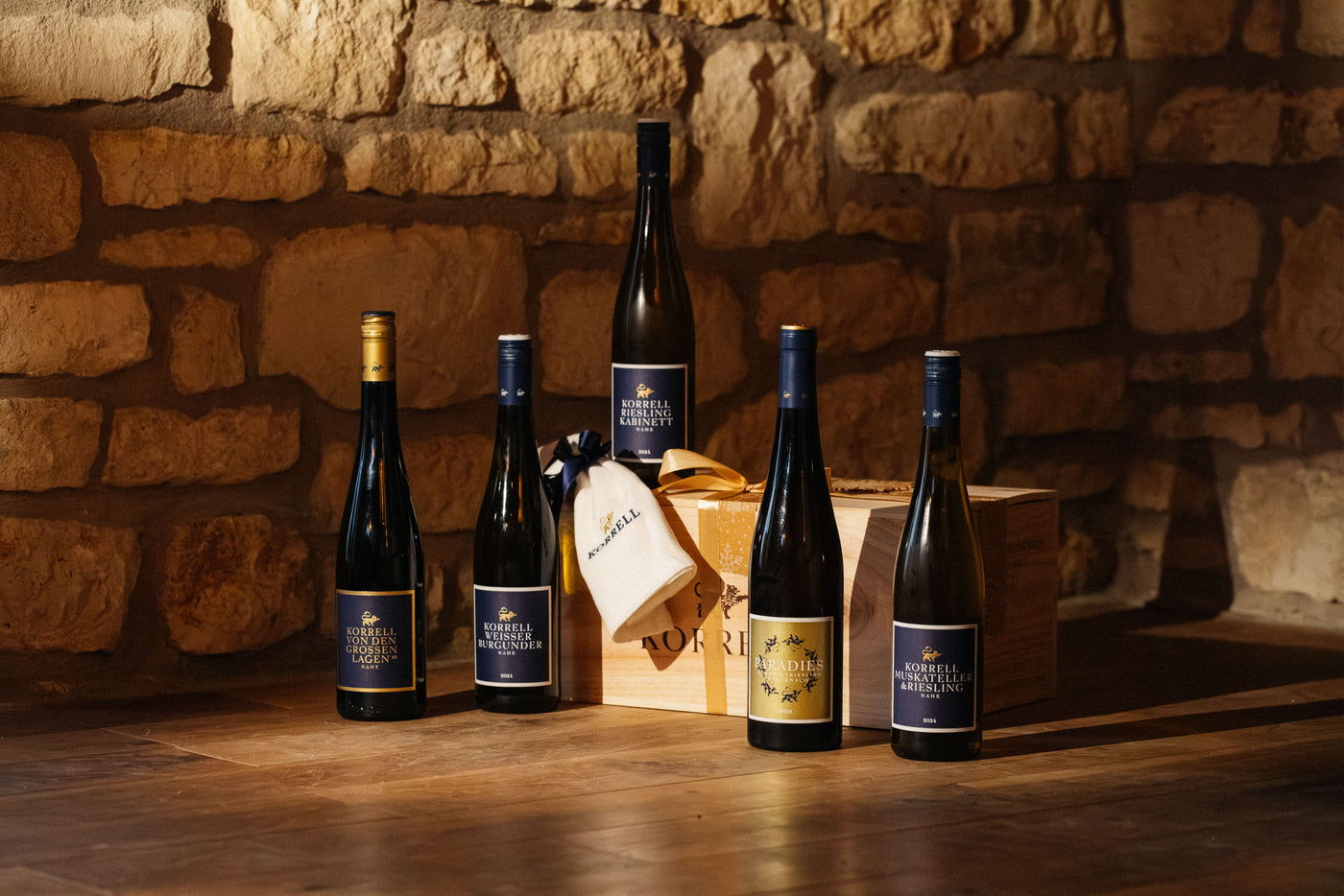 5 Flaschen Wein vor Holzkiste mit Geschirrtuch